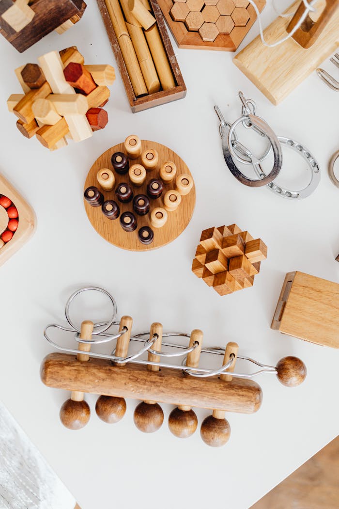 Top view of various wooden puzzles and brain teasers on a white table.